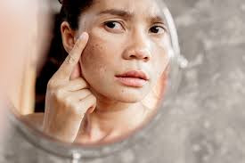 Woman examining small lines and wrinkles in a mirror