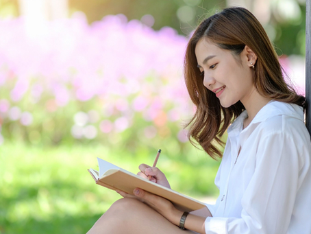 Woman writing in a journal by a tree