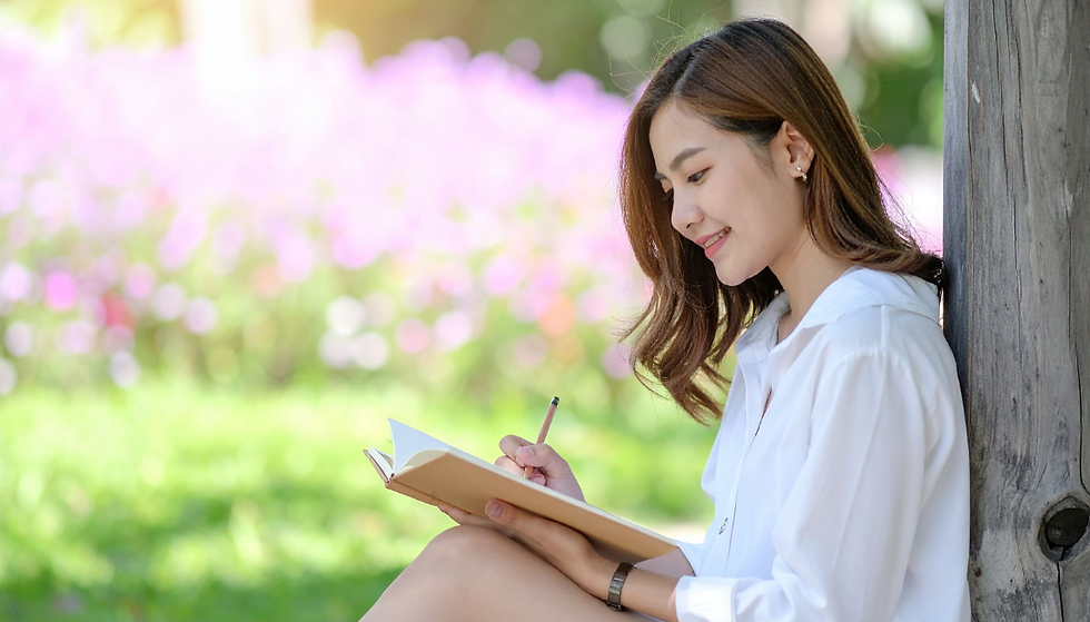 Woman writing in a journal by a tree