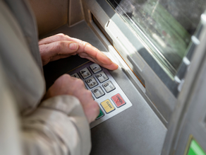 someone covering the pin pad at an atm