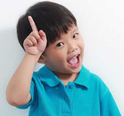 Excited young boy in blue shirt pointing finger up with an idea.