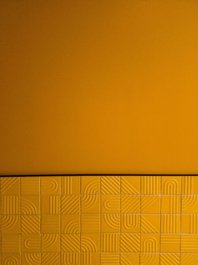 Abstract yellow geometric tiles with textured patterns and smooth wall.