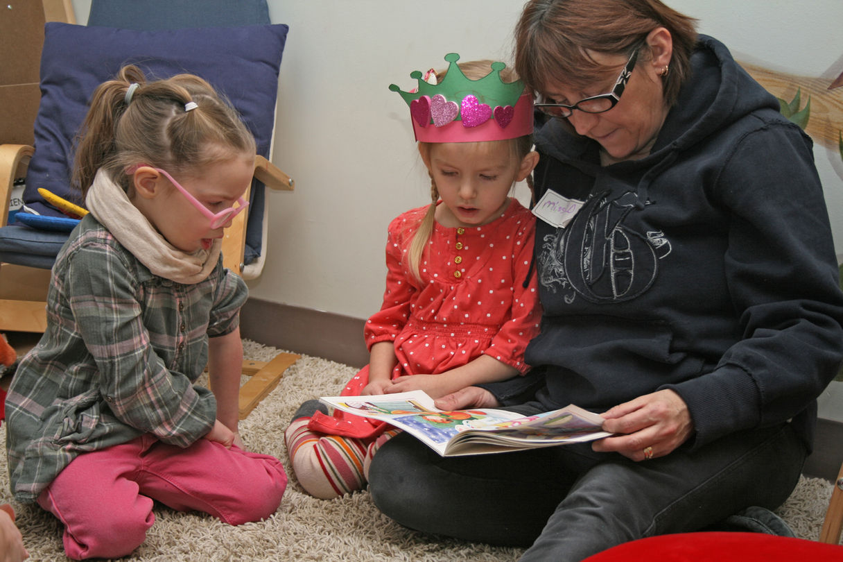 Woman reads storybook to two young girls, GRIT Edmonton.
