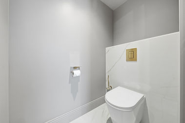 Espace WC séparé, lumineux et épuré, décoré dans des tons clairs avec un habillage effet marbre et des touches dorées. L’ensemble crée une atmosphère moderne, soignée et haut de gamme, parfaitement alignée avec le standing du logement.