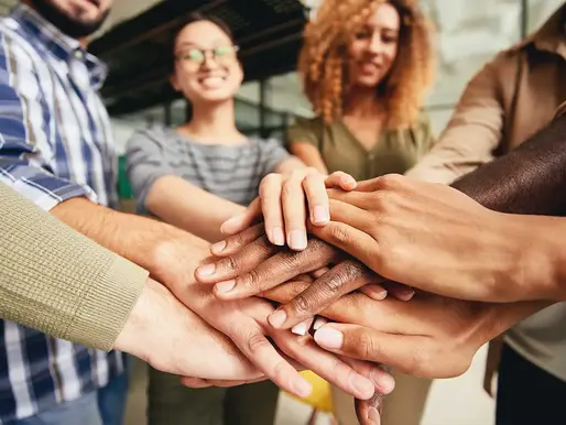 Manos de un equipo apiladas, gesto de compromiso y coordinación