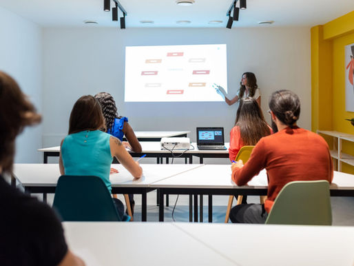 Persona realizando una presentación frente a un grupo de asistentes en una capacitación presencial sobre comunicación y desarrollo profesional.