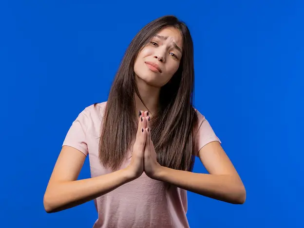 Mujer con gesto de disculpa o arrepentimiento sobre fondo azul, ilustrando el reconocimiento y la gestión consciente de la culpa.