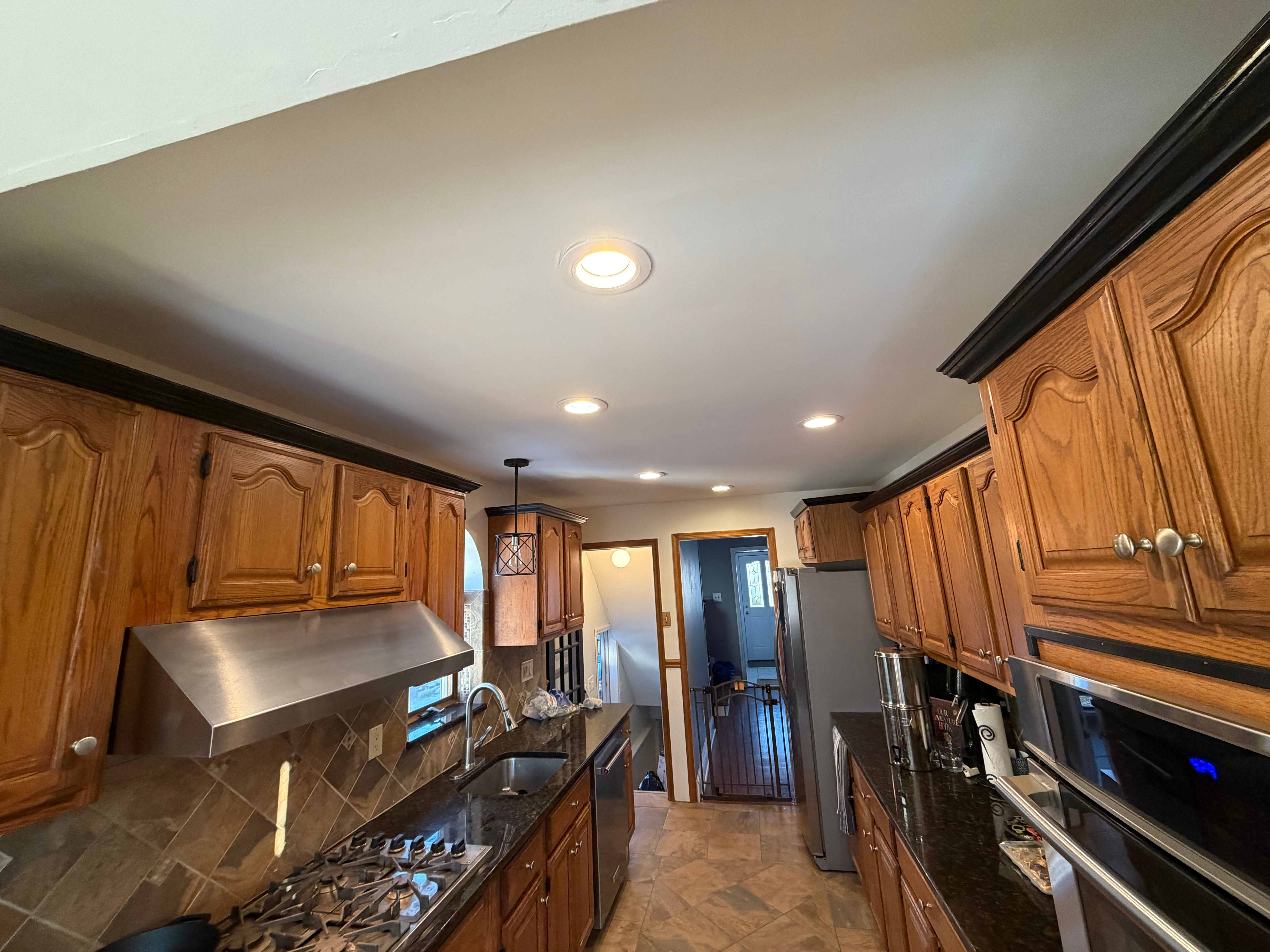 Kitchen tile floor in Bergen County, NJ — slate-pattern tile flooring under oak cabinets and dark granite counters