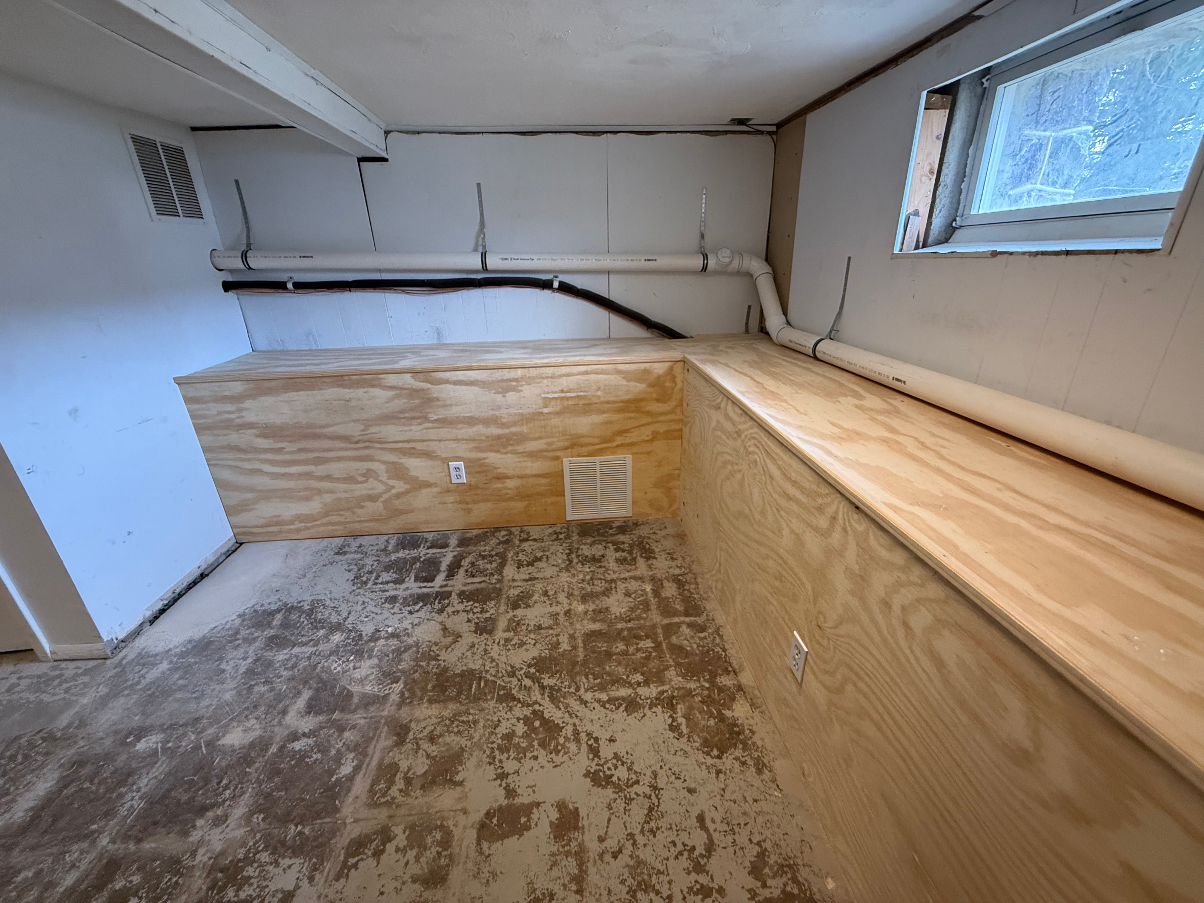 Unfinished basement before remodel in Bergen County, NJ — bare studs, exposed plumbing, dusty floor before HomeGrown Roots & Repairs framing
