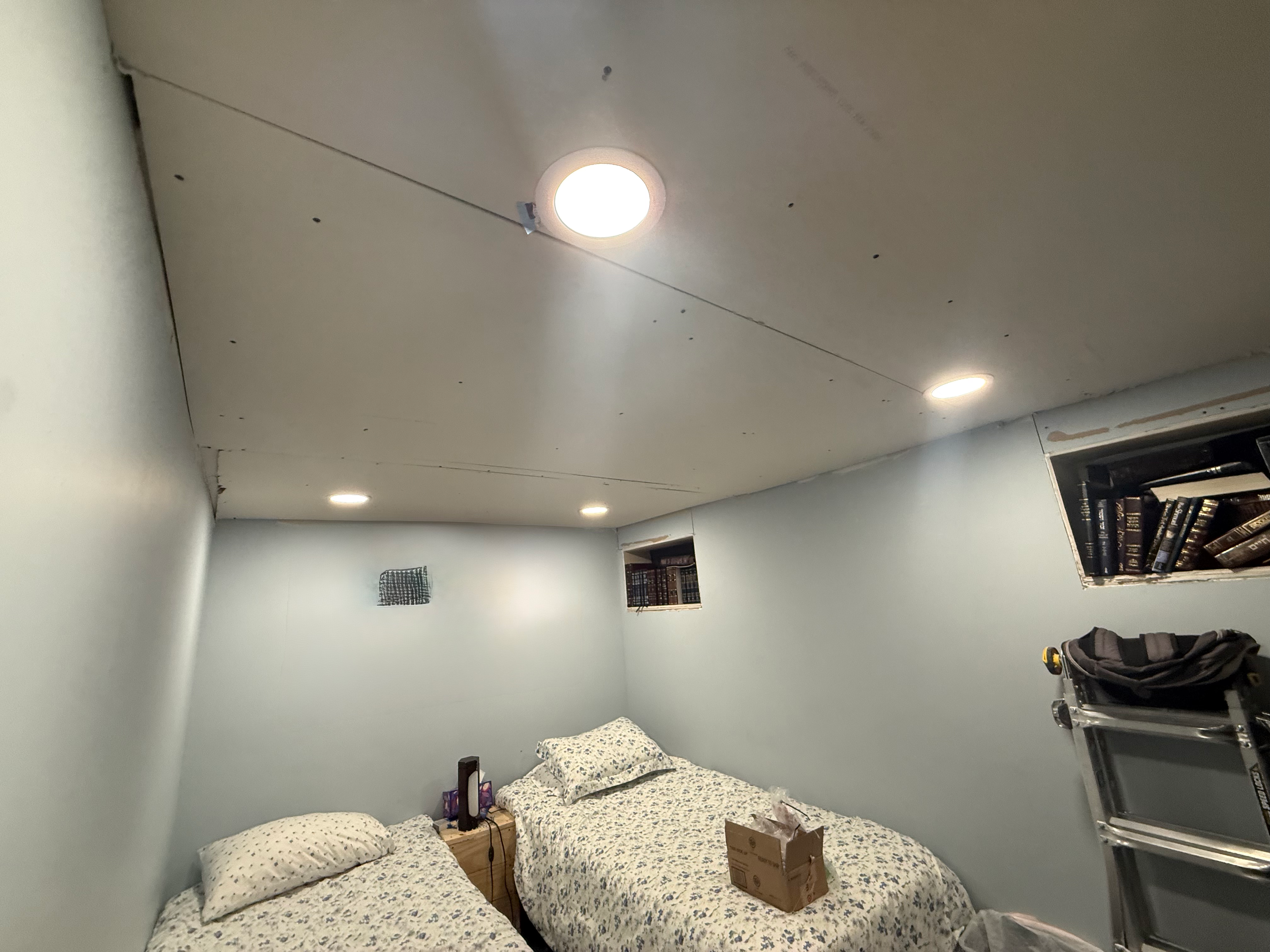 Basement guest bedroom in Bergen County, NJ — twin-bed layout, finished walls, recessed lighting, and proper egress windows