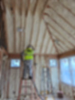 Technician applying spray foam insulation to vaulted ceilings and wall cavities in a resid