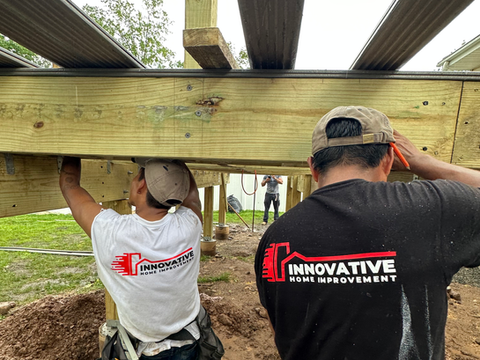Two crew members from Innovative Home Improvement installing a deck from underneath.