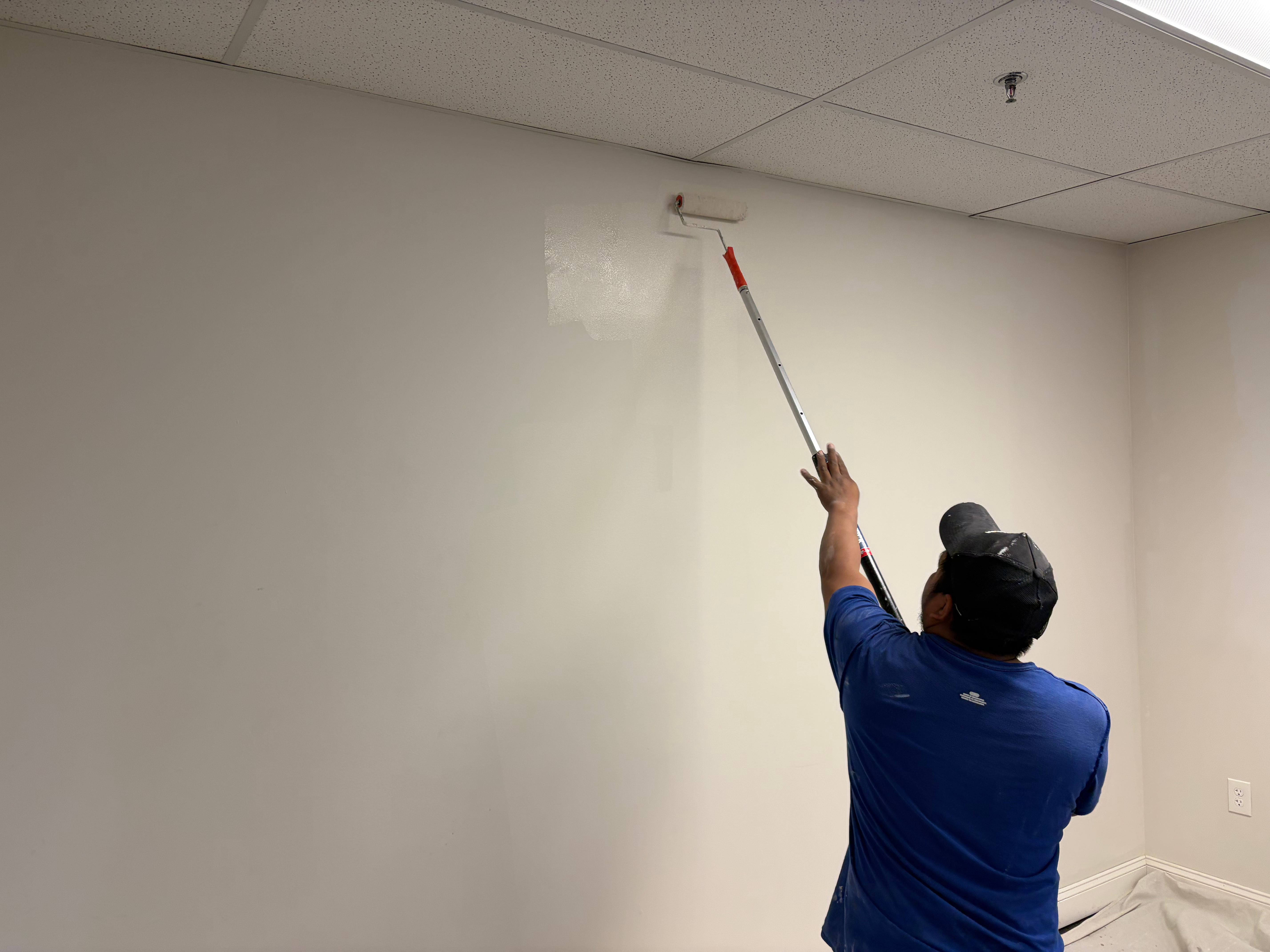 HomeGrown Roots & Repairs contractor rolling fresh paint in Bergen County, NJ — extension pole, careful cut-in, professional finish