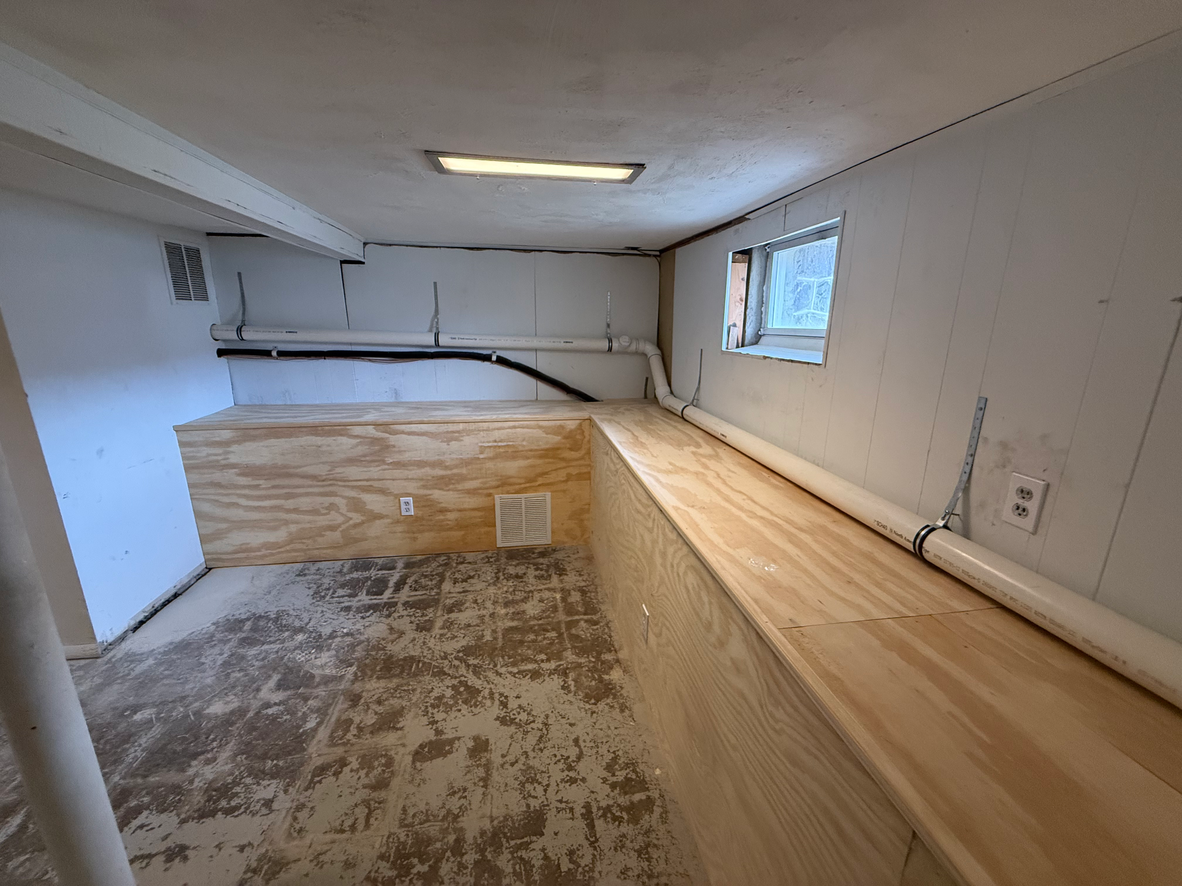Basement before-state in Bergen County, NJ — pre-framing photo showing exposed pipes, ductwork, and concrete floor