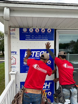 Two crew members from Innovative Home Improvement installing siding on a house.