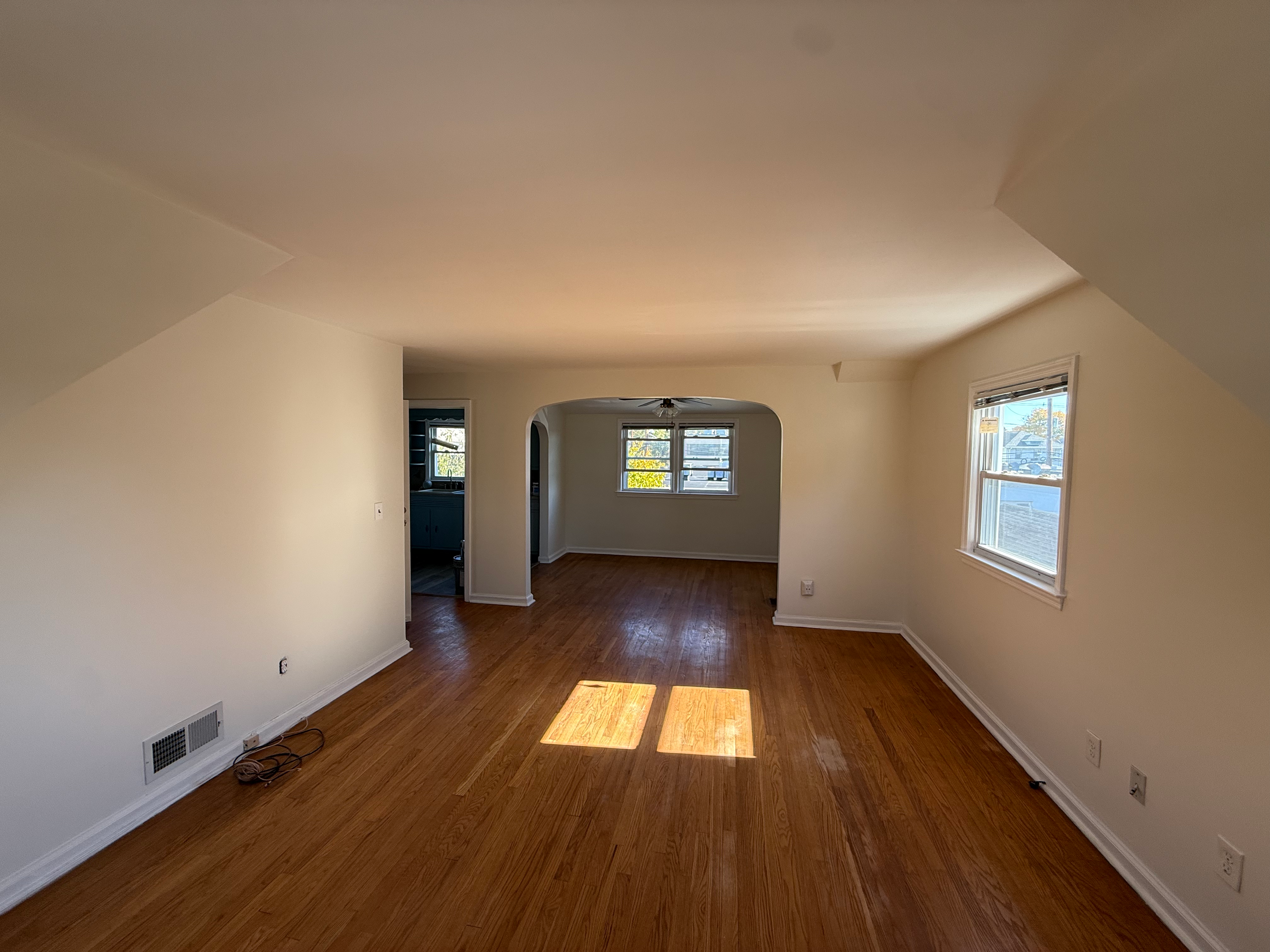 Open living and dining space after interior repaint in Bergen County, NJ — fresh paint, dark hardwood, recessed windows, ceiling fan