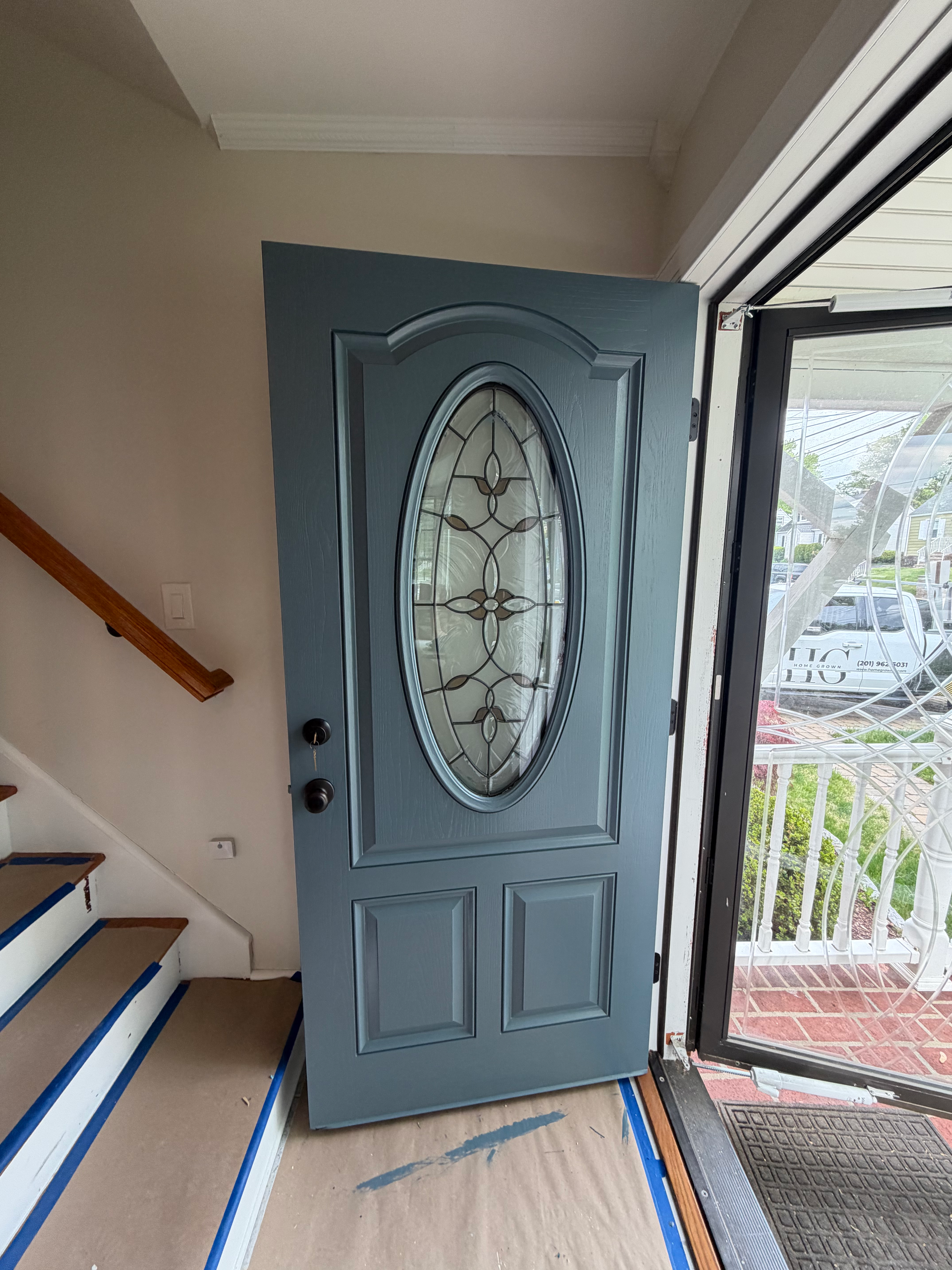 Front door painted teal blue in Bergen County, NJ — careful prep with taped stairs, drop cloths, and leaded-glass insert protected