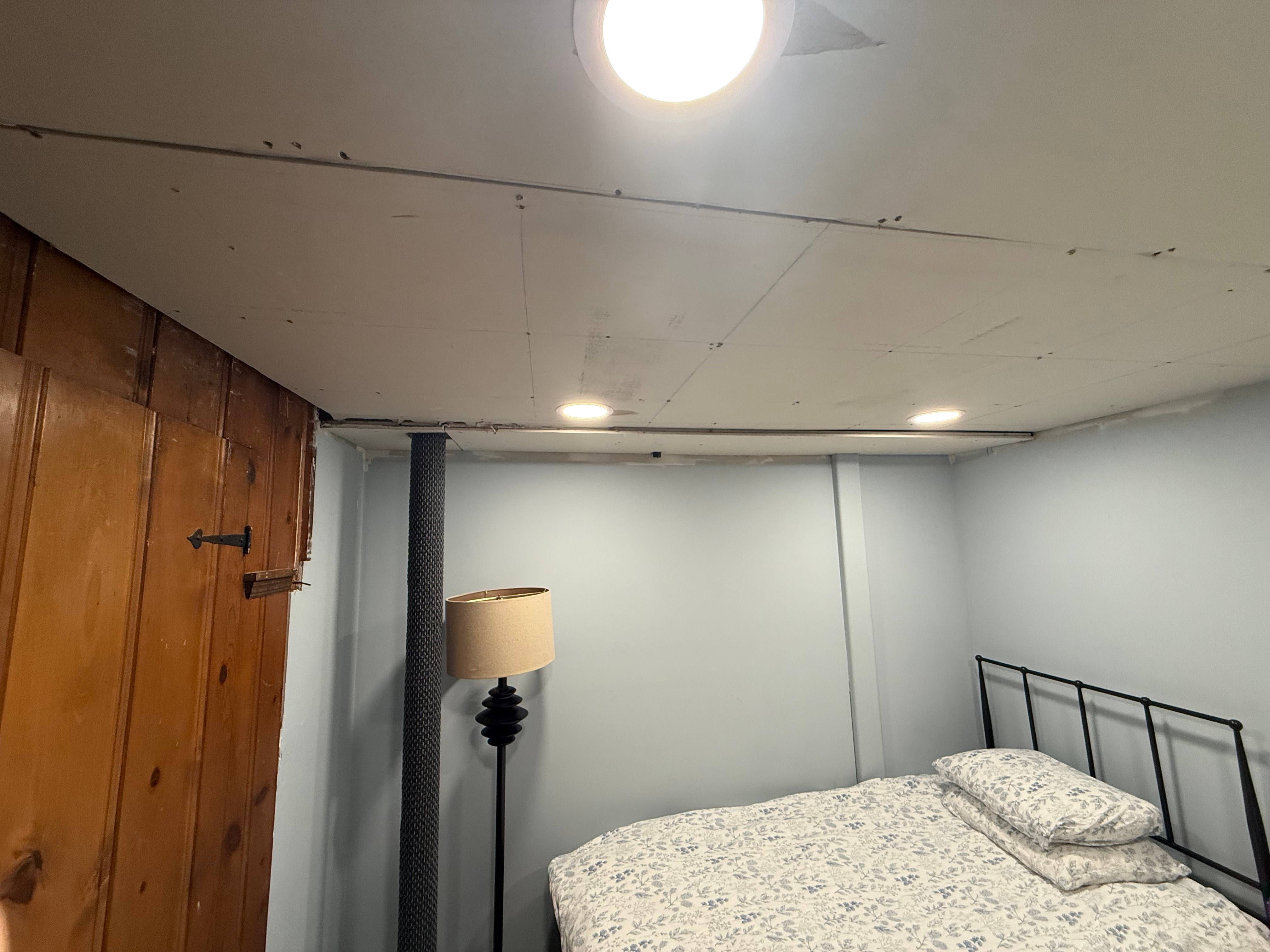 Basement bedroom finished in Bergen County, NJ — egress-compliant build with recessed lights and carpet