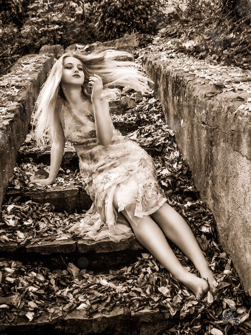 Femme blonde assise sur des marches en béton, cheveux au vent et Olga.