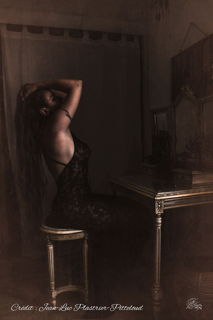 Femme en robe noire assise près d'une coiffeuse avec Reflets De Fawn