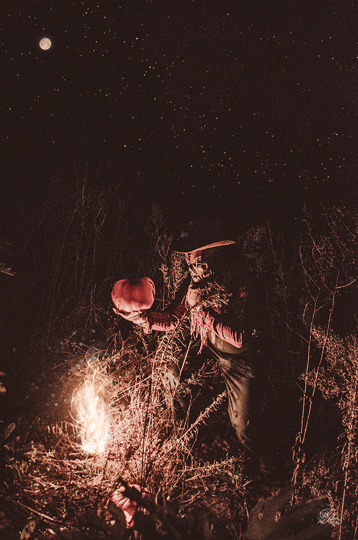 Homme tenant une citrouille illuminée, la nuit, dans la forêt. Reflets De Fawn.