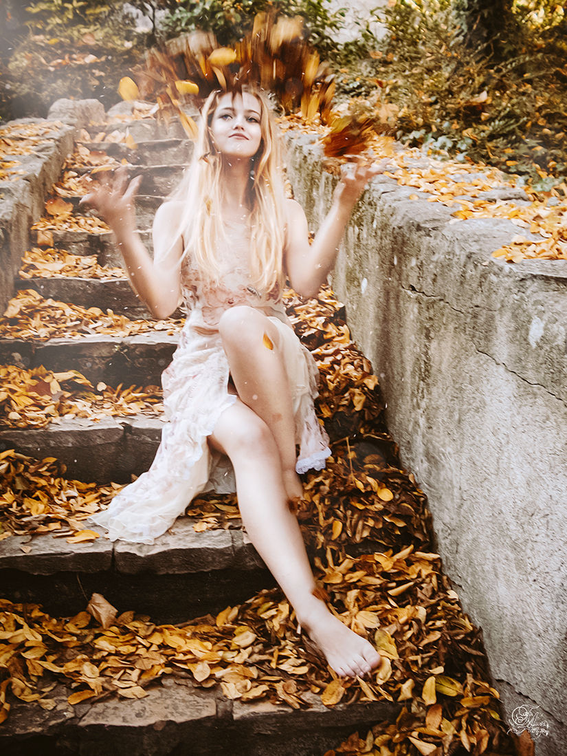 Femme blonde assise sur des escaliers avec des feuilles, Olga. Reflets De Fawn