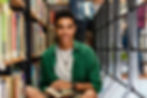 Image of a smiling teen boy sitting in the floor of a library holding a book | therapy for teens in manhattan, ny | teen therapist in manhattan, ny | parenting support | anxiety in teens | online therapy for teens | 10028 | 10013 | 10002