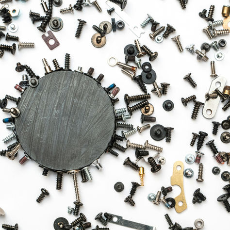 Round magnet with nails, screws and other metal objects attached to or surrounding it