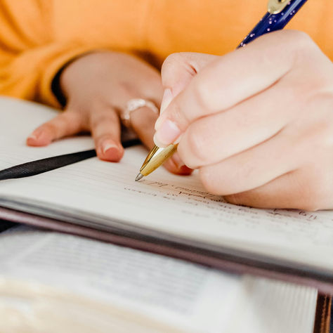 Person writing in a journal with a pen, symbolizing reflection and emotional healing.