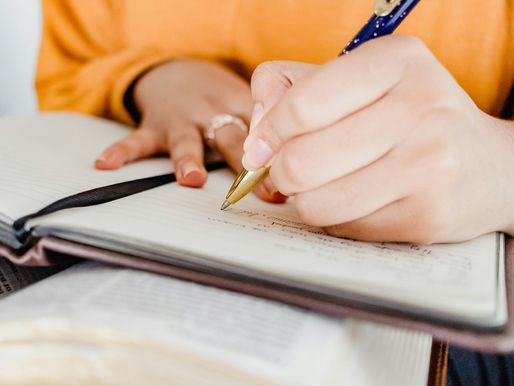 Person writing in a journal with a pen, symbolizing reflection and emotional healing.