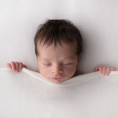 A newborn swaddled in soft fabrics, radiating warmth and purity.