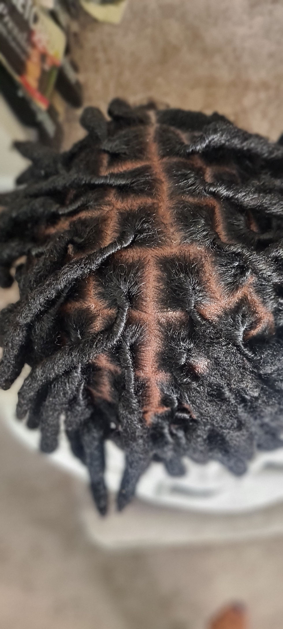 Eye-level view of a person applying natural oil to scalp with dreadlocks