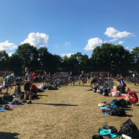 Menschen halten sich auf einem Triathlon-Sammelplatz mit Wechselzone im Freien auf.
