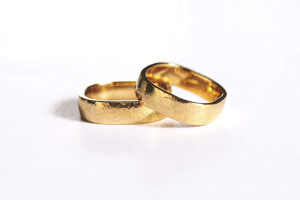 Trauringpaar aus Gelbgold 900 mit fein gehämmerter Oberfläche. Das Paar hat die ungewöhnliche Form eines abgerundeten Quadrats, was sich besonders angenehm trägt.