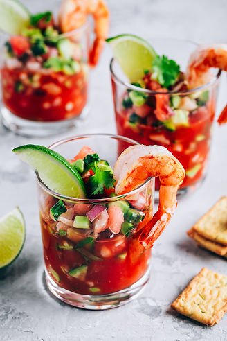 Refreshing Mexican Shrimp Cocktail with lime in glass on gray stone background, copy space