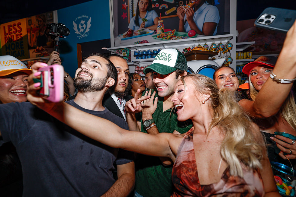 Group of people taking a selfie in a colorful, lively setting. Background text: "Less Rules, More Sugar." Emotions: joyful, festive.