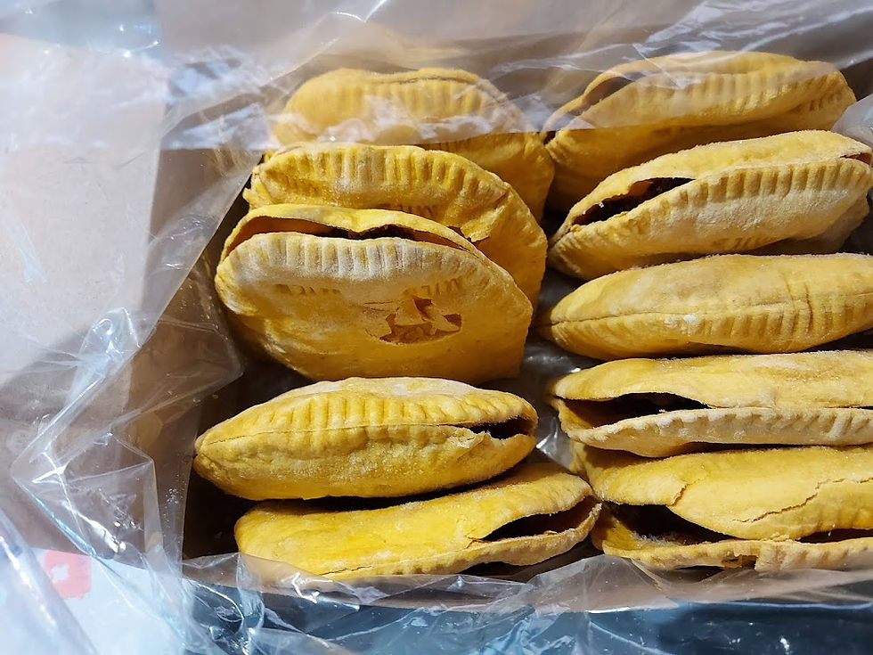Golden-brown baked pastries with crimped edges in a clear plastic bag. They're stacked neatly, displaying a crispy texture.