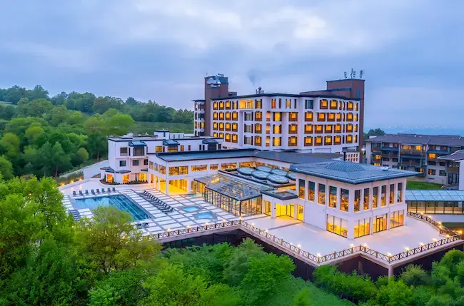 An aerial view of the Narven Wellness & Thermal Hotel, featuring its outdoor pool area and illuminated building facade