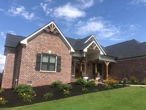 Brick home with lawn maintenance, fresh mulch, and seasonal plants.