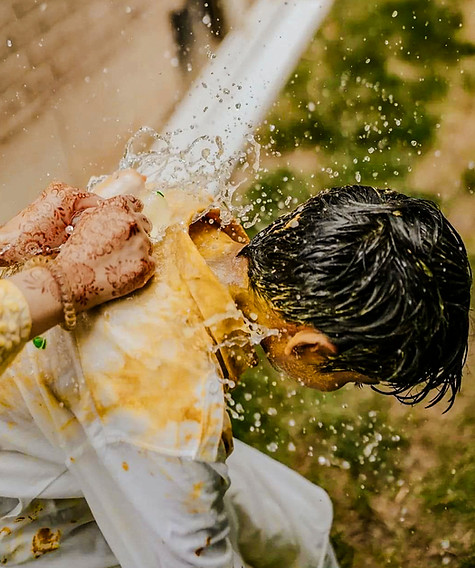 Groom enjoying a playful water splash during the haldi ceremony
