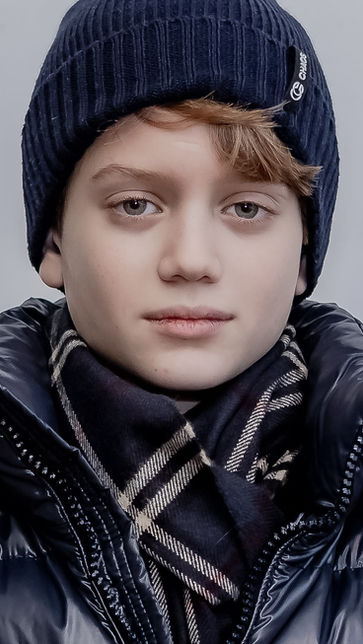 Close-up studio portrait of a child with expressive eyes against a dark background