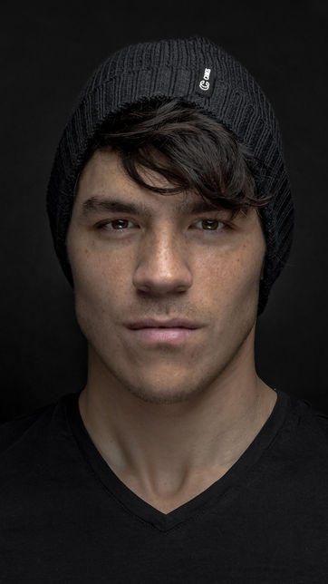 Studio professional headshot of a man wearing a black beanie photographed against a dark background in Boston