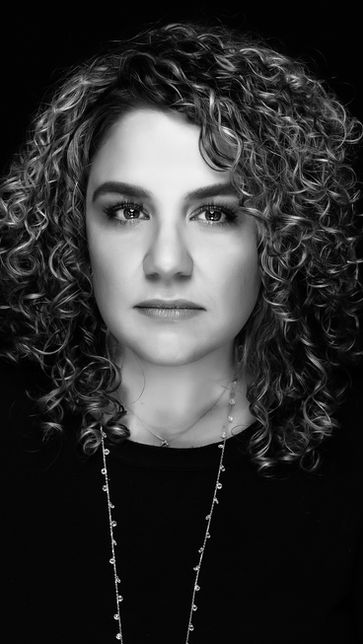 Professional black and white headshot of a woman with curly hair against a black background in Miami