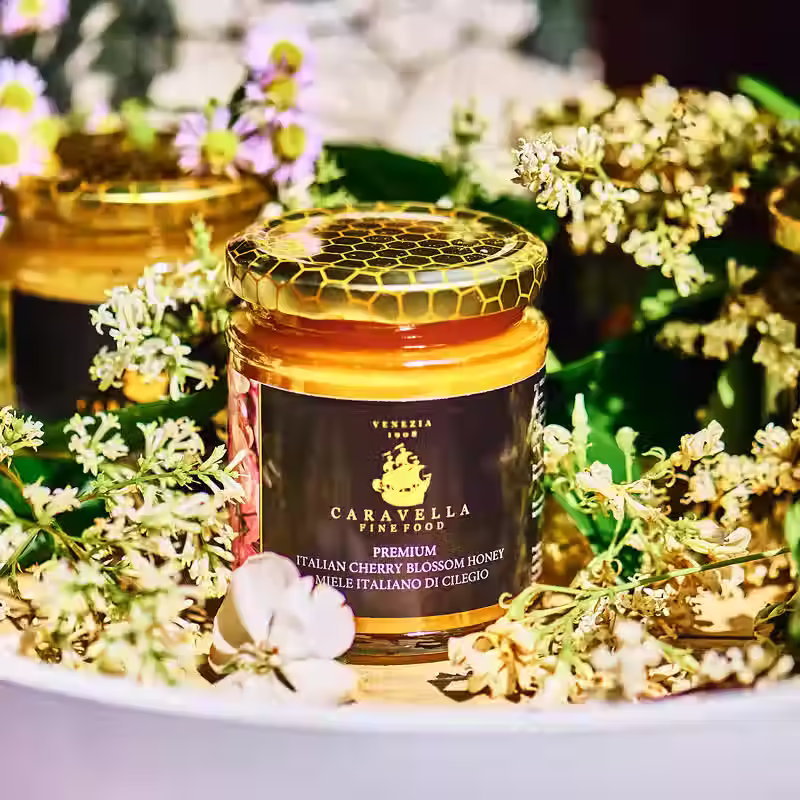 Miniatyrbild: Cherry blossom honey jar by Caravella Fine Food surrounded by blossom flowers