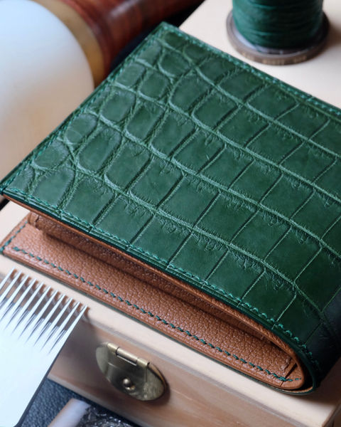 Wallet no. 32 entirely handmade and hand-sewn in green Nile crocodile leather, interior in gold Sully goatskin, deep green linen thread, deep green edge painting and initials marked in real 22k gold.