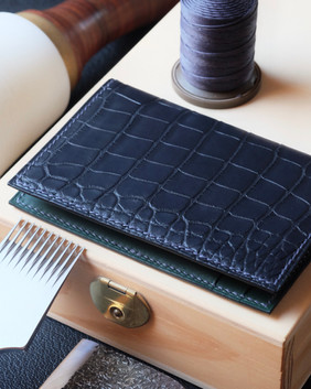 Porte-cartes pliant 20 entièrement fait main et cousu main en cuir d’alligator marine blue, intérieur en cuir de veau lisse Baranil vert, fil de lin dark blue, peinture des bords dark blue et initiales marquées à chaud.
