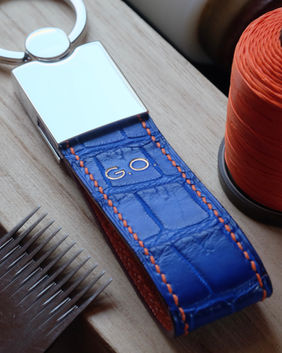 Porte-clés en cuir de crocodile du Nil bleu électrique, doublure chèvre orange, fil de lin orange, peinture des bords violette et marquage des initiales à l’or véritable 22k.