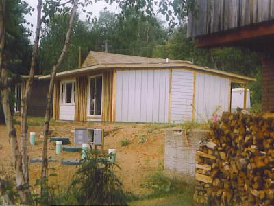 Croftville Road Cottages. Here is Cottage 1 from the lakeside with a mixture of new and recycled siding and trim boards installed. The newly installed septic tanks are in the foreground.