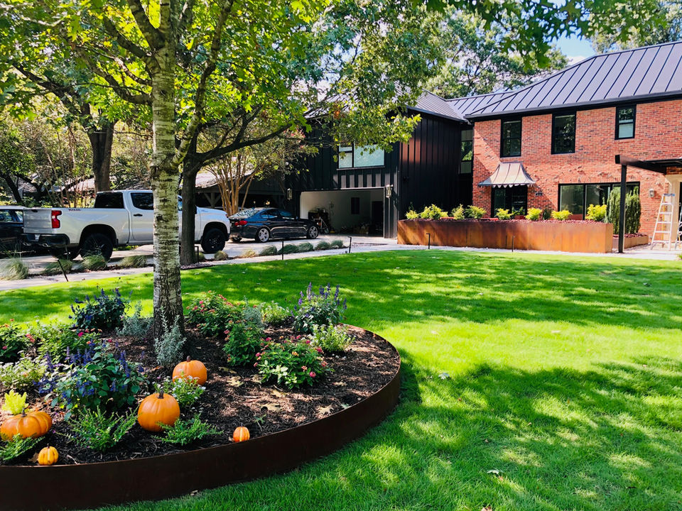 Suburban landscape with colorful plants and rustic accents in front of a newly renovated 1930s home on Santa Clara Dr. in Dallas, TX.