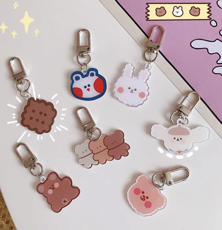 Mehrere kawaii Schlüsselanhänger mit Bären- und Hasenmotiven neben einem Checklistenblock und AirPods Case